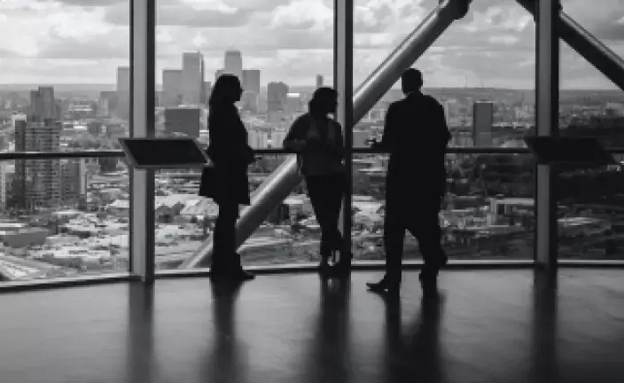 an image of three people looking out a window at a city skyline